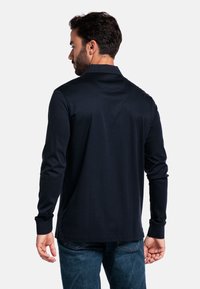 Dunkelblaues Langarm-Polohemd mit Kragen, das eine glatte Textur und eine taillierte Silhouette aufweist. Sichtbare Nähte entlang der Nähte und Bündchen.