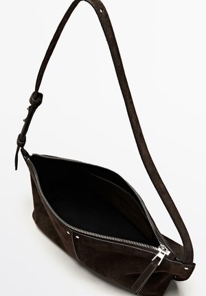 Mørkebrun skuldertaske i ruskind med sølvlynlås delvist åben, justerbar rem og synlig indvendig lomme mod hvid baggrund.