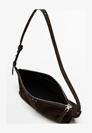 Mørkebrun skuldertaske i ruskind med sølvlynlås delvist åben, justerbar rem og synlig indvendig lomme mod hvid baggrund.