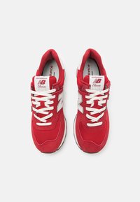 Punajuha urheilusandaalit, joissa on verkkokangas ja mokkamateriaali; valkoiset nauhat, brändäys kielellä ja sivulogolla; pehmustettu pohja ja musta ulkopohja.