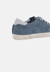 Baskets en daim bleu avec un talon en cuir gris, perforées sur le côté pour la ventilation, et une semelle blanche usée, mettant en avant un design décontracté.