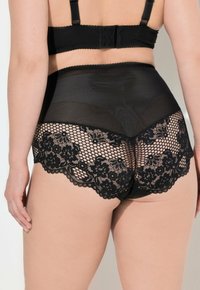 Set di lingerie nera con design in rete e pizzo. Parte bassa alta con bordo in pizzo floreale e dettagli a onde per un tocco in più.