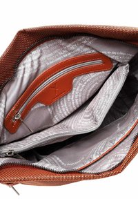 Bolso naranja con textura y cremallera abierta, mostrando el forro interior de color gris claro con texto y varios compartimentos con cremallera en el interior.
