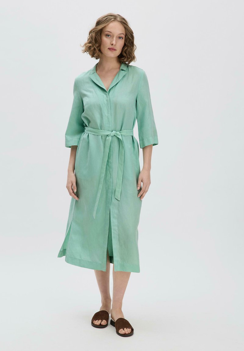 Mintgrünes Leinenkleid mit Kragen, Dreiviertelärmeln und gebundenem Taillenbereich. Verfügt über einen vorderen Schlitz und eine glatte, leichte Textur.
