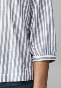 Blusa a righe in cotone blu e bianco con una vestibilità rilassata, caratterizzata da maniche corte arricciate e orlo dritto.