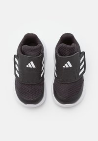 Czarne buty sportowe z teksturowaną cholewką, wyściółką wokół kostki i regulowanym paskiem. Posiadają białe logo w postaci trzech pasków oraz białą podeszwę.