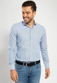 Lichtblauw gestreept overhemddesign in een katoenmix, met een standaard kraag, knoopsluiting en lange mouwen, gecombineerd met denim jeans en een zwarte riem.