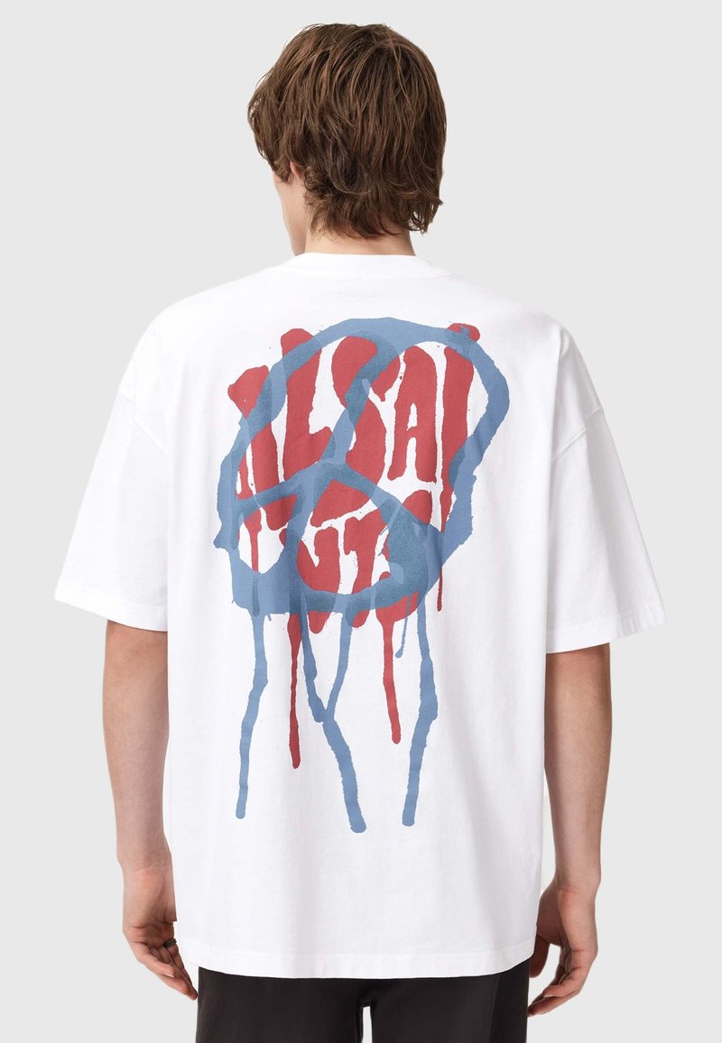 Hvit bomulls t-skjorte med et stort abstrakt design i blått og rødt på baksiden, med dryppdetaljer og en avslappet passform.