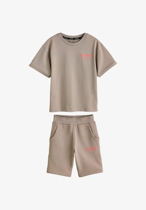 Set composto da T-shirt beige a maniche corte e pantaloncini con vita elastica, entrambi con piccolo logo rosso "ALLSAINTS" sul petto sinistro e sulla coscia.