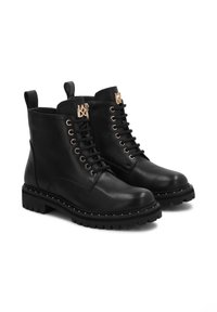 Botine din piele neagră cu șireturi și accente din metal aurit, având o talpă groasă din cauciuc cu țepi și o buclă în spate.