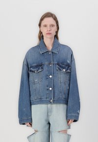 Veste en denim avec un design court, des fermetures à boutons, deux poches poitrine et des détails usés ; elle présente une couleur bleue classique et des manches larges.
