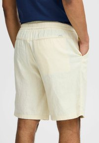 Lichtbeige shorts met een elastische tailleband, zijzakken en een textuurstofafwerking. Casual ontwerp, geschikt voor warm weer.