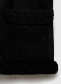 Svart fleece tyg med plysch, texturerad svart kant. Har en slät yta och djup färg som framhäver de mjuka materialen.