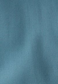 Tissu bleu texturé avec un motif tissé serré à petite échelle et de légers plis en surface.