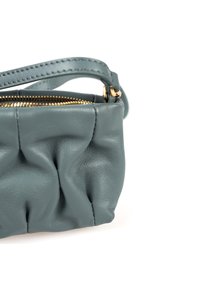 Borsa in pelle color teal con texture arricciata e zip tono oro. Presenta una maniglia corta e una forma compatta e arrotondata.