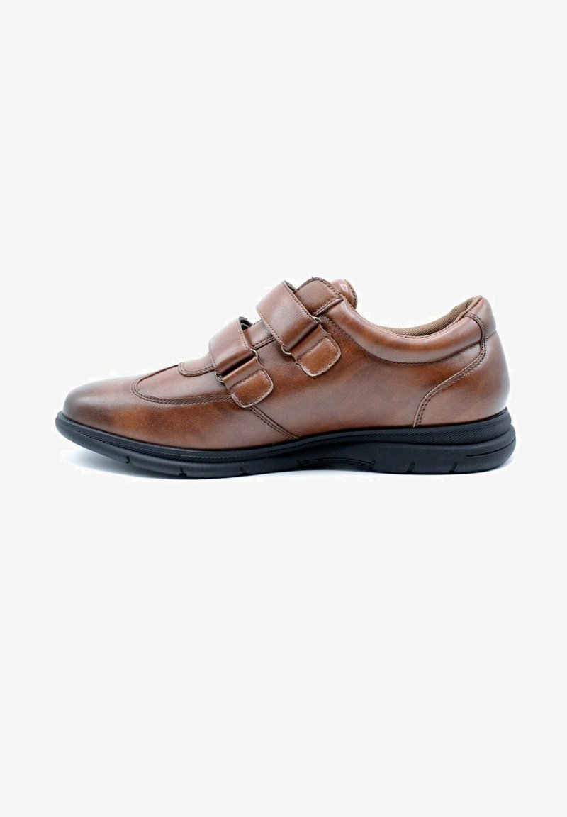Chaussure en cuir marron avec deux sangles velcro, bout rond, semelle en caoutchouc noir et détails de couture subtils.