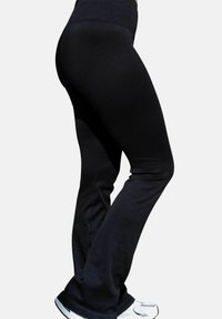 Svarta leggings i ribbad tyg med hög midja och utsvängda ben, kombinerade med vita sportskor.