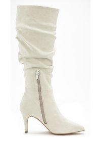 Cremfarbene, lässige Stiefel aus weichem Wildleder, mit einer spitzen Zehenform, einem eng anliegenden Schaft und einem seitlichen Reißverschluss für einfaches An- und Ausziehen.