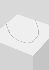 Silver chain necklace featuring small star and crescent moon charms, with a smooth texture and delicate design.