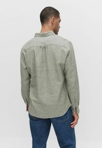 Groene linnen overhemd met een kraag, lange mouwen en knoopmanchetten. Heeft een gestructureerde stof en een yoke-detail aan de achterkant.