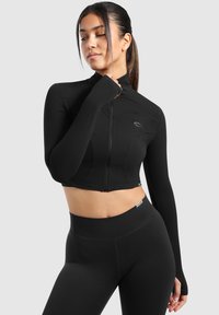 Schwarze, kurz geschnittene Sportjacke mit langen Ärmeln, hohem Kragen und Frontreißverschluss. Verfügt über glattes, elastisches Material und dezente Logodetails.