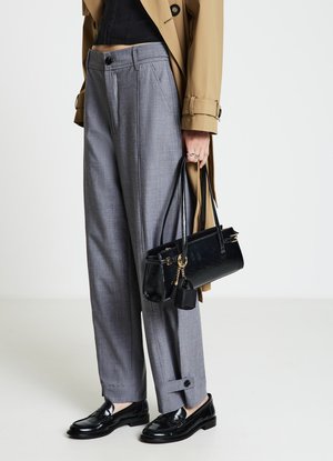 Pantaloni grigi a gamba larga con un motivo sottile, abbinati a mocassini neri in vernice e una borsa nera lucida con dettagli dorati.