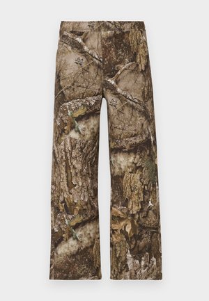 Camo print pants in brown, featuring a wide-leg design and elastic waistband. Material resembles textured tree bark with leaf accents.