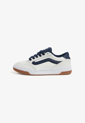 Baskets blanches en cuir avec des accents bleu marine, à bout rond et à laçage. Semelle texturée avec une adhérence en caoutchouc et détails perforés sur le côté.