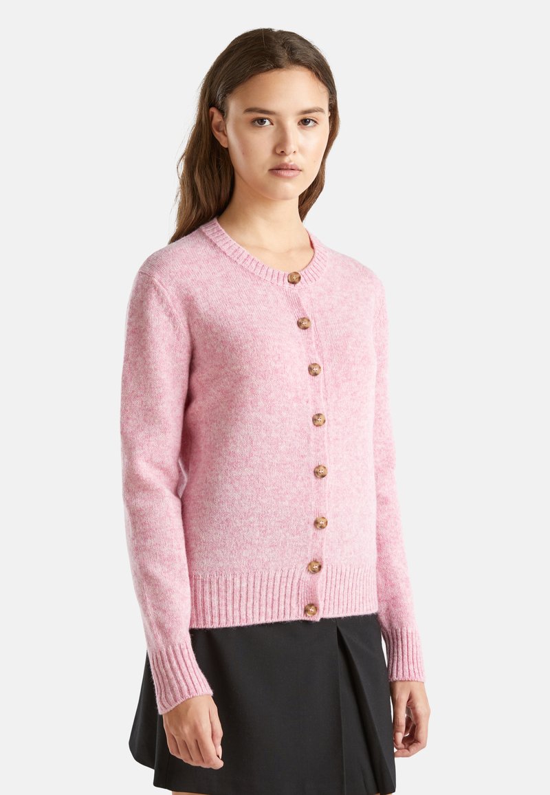 Růžový vlněný cardigan s kulatým výstřihem, sedmi knoflíky vpředu, žebrovanými manžetami a lemem. Měkká textura s mírným melírováním.