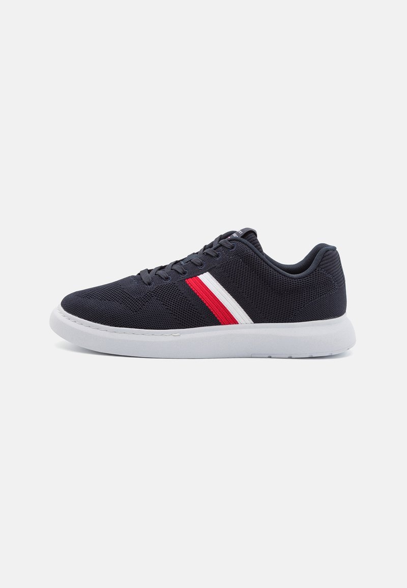 Baskets en mesh noir avec des bandes blanches et rouges sur le côté, semelle blanche et lacets noirs, vues en profil droit.