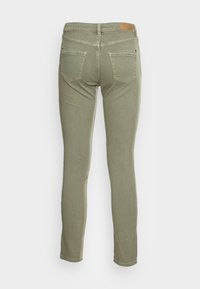 Slim-fit olijfgroene jeans met twee achterzakken, riemlussen en een rechthoekig lederen label op de tailleband, gezien van achteren.