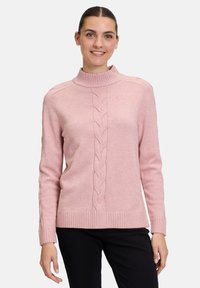 Helle rosa gestrickter Pullover mit hohem Kragen, der ein zentrales Zopfmuster sowie gerippte Bündchen und Saum aufweist. Weicher Griff und lockere Passform.