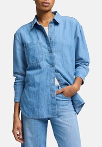 Jasnoniebieska bawełniana koszula z guzikami, z wyłożonym kołnierzykiem, pojedynczą kieszenią na piersi i długimi rękawami. Charakteryzuje się luźnym krojem i subtelną teksturą.