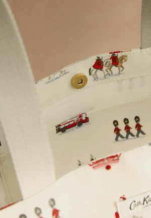 Lõuendist käekoti sisu, kreemikat värvi, millel on printitud mustris valvurid, hobused ja tuletõrjeauto. Kuldse kinnituse detail kinnitub klõpsuga.