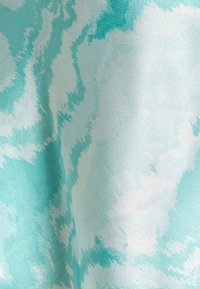 Texturerat tyg i mjuka nyanser av aqua och vitt, med ett molnliknande mönster i blandade färger och en slät yta.