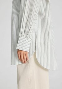 Lichte, gestreepte blouse met lange mouwen en een afgeronde zoom. Beschikt over knoopmanchetten en subtiele pastelkleuren.