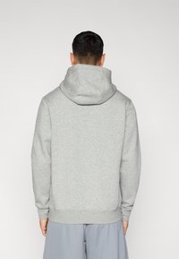 Γκρι φούτερ με μεγάλη κουκούλα, μακριά μανίκια και ριμπ μανσέτες. Μαλακό βαμβακερό υλικό με διακριτική υφή. Η πίσω όψη δείχνει άνετη εφαρμογή.