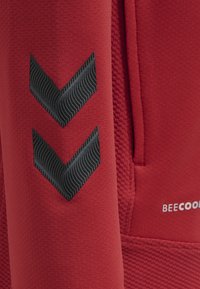 Roter Stoff mit einer strukturierten Oberfläche, der zwei schwarze Zickzackformen zeigt, die geschwungene Linien darstellen. "BECOOL"-Logo in Weiß am unteren Rand.