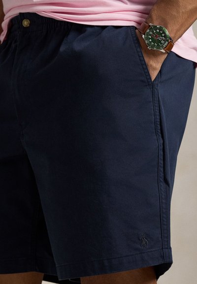 Tmavomodré šortky z bavlny s voľným strihom, bočnými vreckami a malým logom na leme. Elastický pás so zapínaním na gombík.