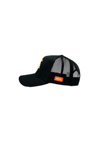 Gorra negra con un frontal sólido y parte trasera de malla. Presenta un visera curva y una etiqueta naranja en el lateral. Decorada con diseños gráficos.
