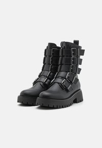Black ankle boots made of leather, featuring multiple adjustable buckle straps on the shaft and a chunky textured platform sole.