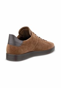 Sneaker in suede marrone con tacco in pelle marrone scuro. Caratterizzato da una punta rotonda, lacci piatti e una suola in gomma flessibile e testurizzata.