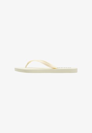 Una sandalia chancla beige con tiras finas y suela plana, vista de lado sobre un fondo blanco.