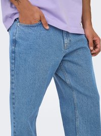 Klassikalised sinised denimpüksid lõdva istuvusega, viis taskut, peene õmblusega ja heleda pesu tekstuuriga.