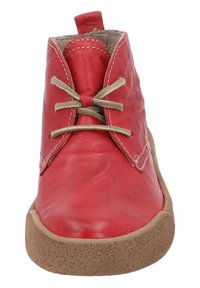 Rød læderstøvle med beige snørebånd, rund tå og tan gummisål. Har synlige syninger og en pull tab bagpå for nem påtagning.