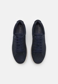 Granatowe sneakersy z gładką skórzaną cholewką, dopasowanymi sznurowadłami i beżową gumową podeszwą. Lekka konstrukcja o opływowym kształcie.