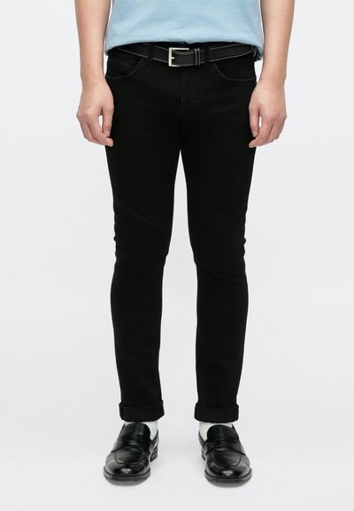 Jean skinny en denim noir avec une légère élasticité, présentant un design à cinq poches, des ouvertures de jambe étroites et un ourlet retroussé aux chevilles.