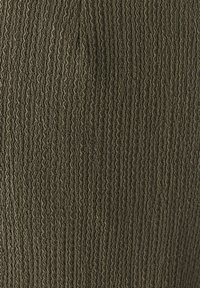 Tissu texturé en vert olive avec des côtes verticales, créant un motif en relief. La surface a une apparence douce et légèrement froissée.