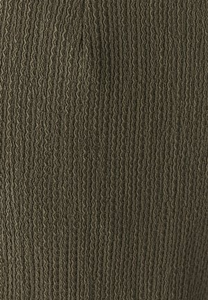 Tissu texturé en vert olive avec des côtes verticales, créant un motif en relief. La surface a une apparence douce et légèrement froissée.