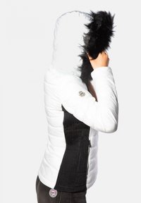 Doudoune blanche avec des panneaux latéraux côtelés noirs. Elle possède une capuche ajustée avec une bordure en fourrure noire et une écusson logo sur l'épaule gauche.